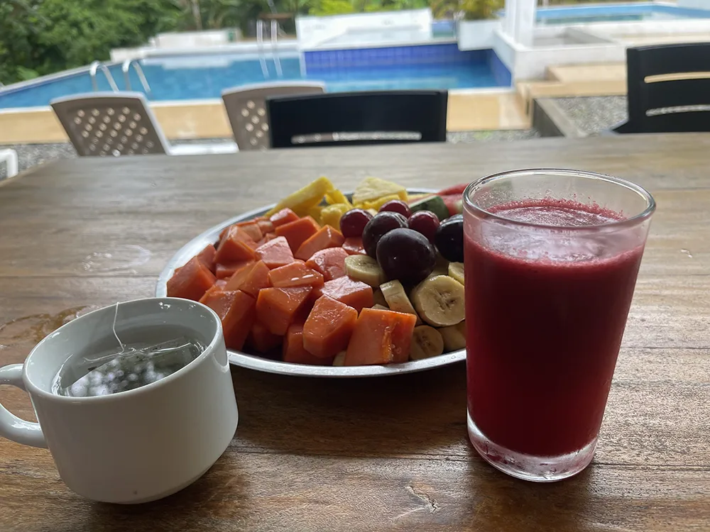 Fresh fruit plate with papaya, banana, grapes, herbal tea, and natural juice served at an ayahuasca retreat in Colombia.